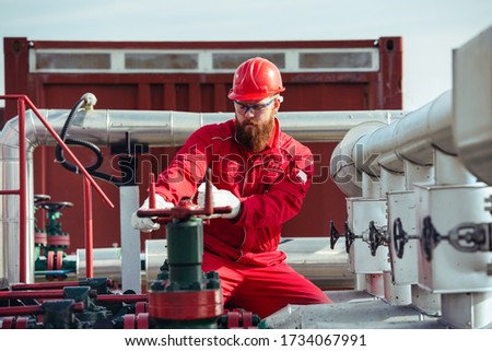 Oil worker turning valve on oil rig Royalty-Free Stock Photo #1734067991