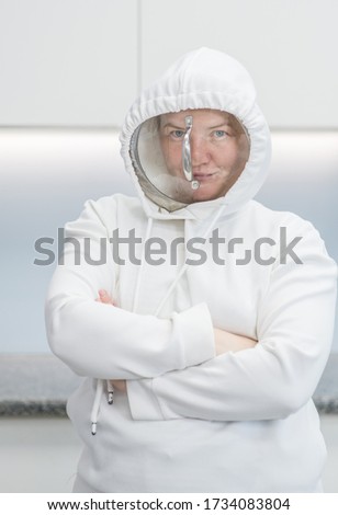 Woman fooling around at home during coronavirus quarantine, dressed up in a funny protective suit with a pan cover