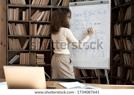 Female latin indian math school teacher or student writing equation on whiteboard in classroom. Virtual live remote teaching concept. Distance online education exam preparation elearning course. Royalty-Free Stock Photo #1734087641