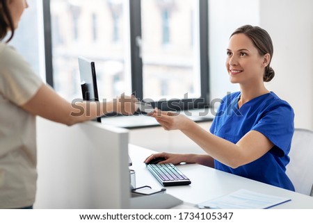 medicine, people and healthcare concept - happy smiling female doctor or nurse and patient with insurance or credit card card at hospital Royalty-Free Stock Photo #1734105347