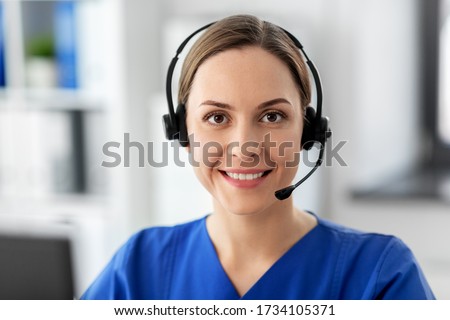 medicine, technology and healthcare concept - happy smiling female doctor or nurse with headset and computer working at hospital Royalty-Free Stock Photo #1734105371