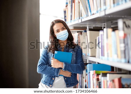 education, healthcare and pandemic concept - student girl wearing face protective medical mask for protection from virus disease with book at library Royalty-Free Stock Photo #1734106466