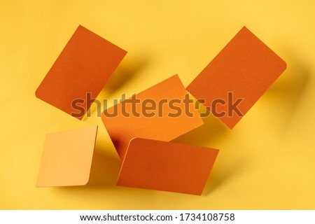 Thick orange business cards with a rounded corner, floating on a yellow paper background, a mockup for a creative design presentation