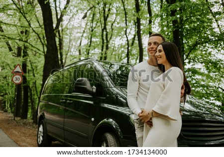 Young pregnant woman with her husband enjoying the nature. Traveling on family car in the field.