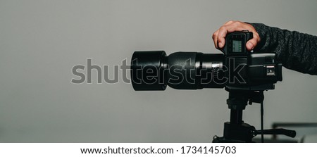 Camera full frame is shooting with professional photographer hand, isolated on studio background