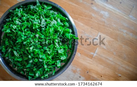 finely chopped and cut spinach for the indian spinach curry in the steel plate with wooden background. Royalty-Free Stock Photo #1734162674