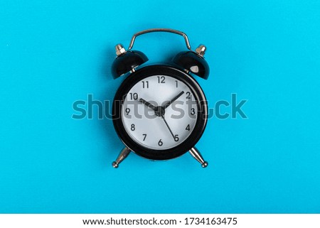black vintage alarm clock on a blue background, top view. concept of time, daily routine