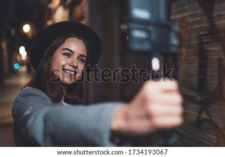 Traveler female blogger shooting video for shoot social media with digital camera. Smiling  woman taking selfie vlog video on light night city