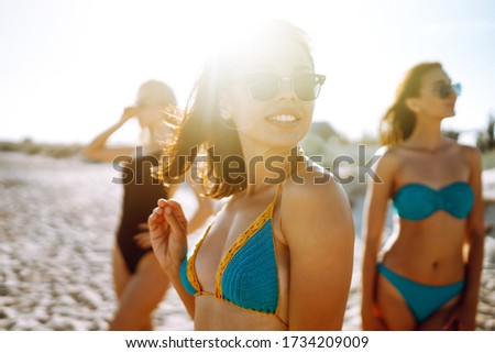 Three attractive women enjoying a holiday on the sea shore. Summer, relax and lifestyle concept.