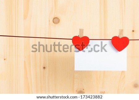 two decorative red hearts with greeting card hanging on wood background with space for text, concept of valentine day