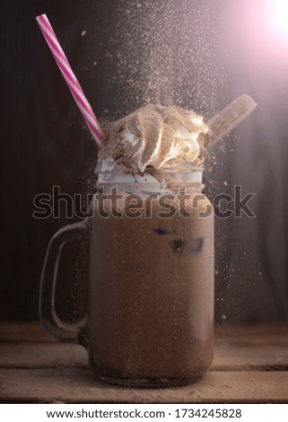 cocoa smoothie with cream, with falling shavings, on dark background
