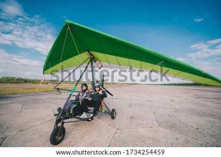 Hang-gliding with two people, standing at dawn on the runway. Front view