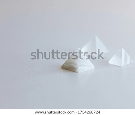 
White pyramids on white table.