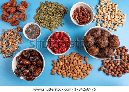 Collection of Superfoods in Bowls for health, fitness and vitality used for preparing energy balls. Top view. Blue background.