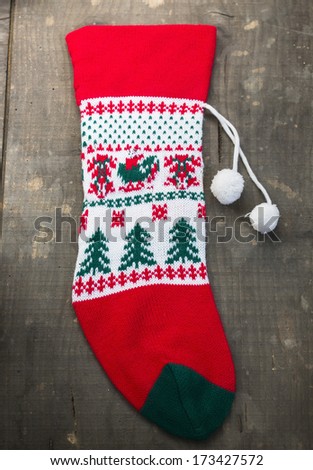 red and green christmas sock with snowflakes for Santa gifts hanging on wooden background. holidays symbol stocking 