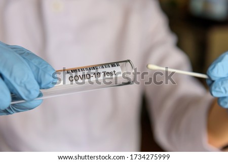 Medical worker holding swab sample collection kit, test tube for performing patient nasal swabbing. Hands in gloves holding testing equipment for Coronavirus COVID-19 diagnostic. Royalty-Free Stock Photo #1734275999