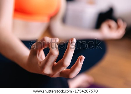 Close up of hands girl working out on fitness mat, doing lotus yoga pose at the home. Yoga exercise, relax and meditating.