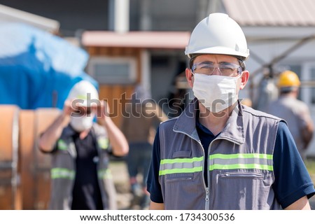 The worker (staff, engineer) protects himself from covid-19 (coronavirus) with a protective mask in the construction site. Royalty-Free Stock Photo #1734300536