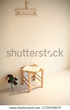 Simple wooden style interior with book, chair, and flower