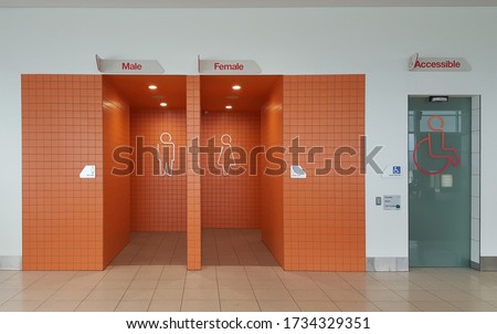 View of the lady, gentlemen and accessible's public toilet or bathroom entrance with bright orange tiles.