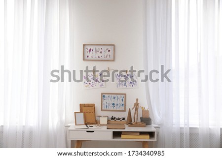 Stylish room interior with creative workplace near white wall