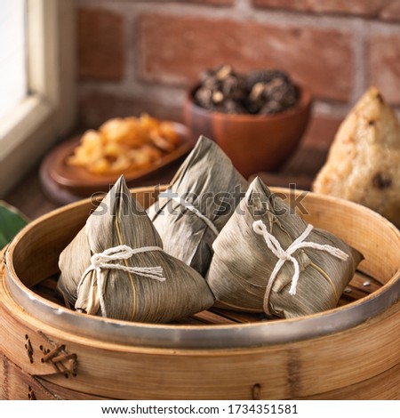 Rice dumpling, zongzi - Chinese rice dumpling zongzi in a steamer on wooden table with red brick, window background at home for Dragon Boat Festival concept, close up.