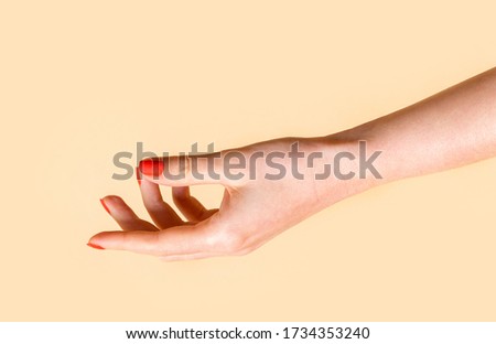 Empty open female hand with red manicure on a beige background. Female hand showing something