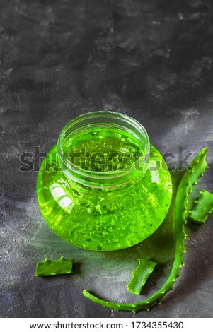 Aloe Vera gel in a jar and green aloe leaf on a grey background. Extract of aloe for natural cosmetic and alternative medicine