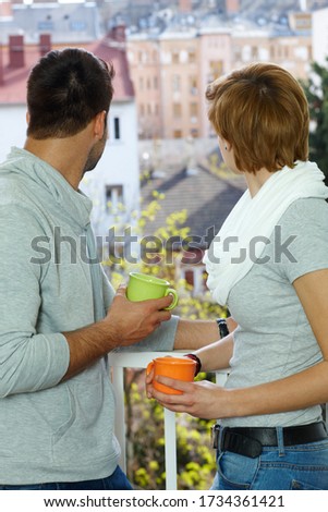 Young couple searching distance, standing at the balcony.