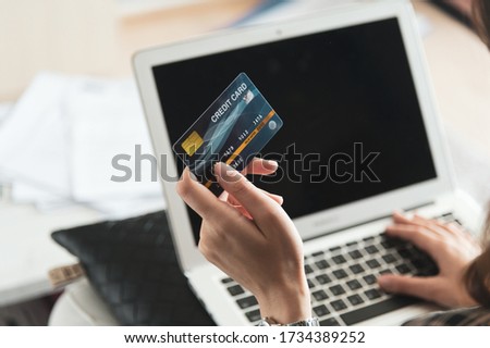 Young Asian woman using credit card for shopping online at her home