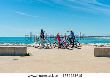 Family on bicycles looking at the beach on sun shining travel vacation day blue sky coastline outdoors background. Horizontal shot. Back view picture of happy exciting people on holiday