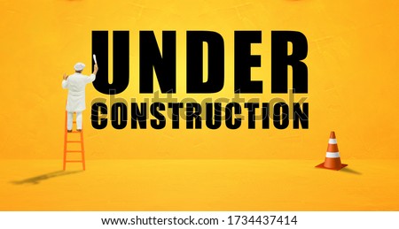 Under Construction and Building Concept : Miniature people as painter painting text wordings Under Construction on yellow concrete grunge texture background.