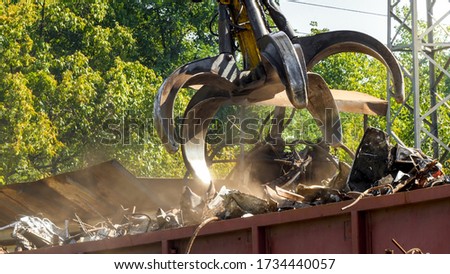 Claw gripper working on metal scrapyard with old rusty pieces Royalty-Free Stock Photo #1734440057