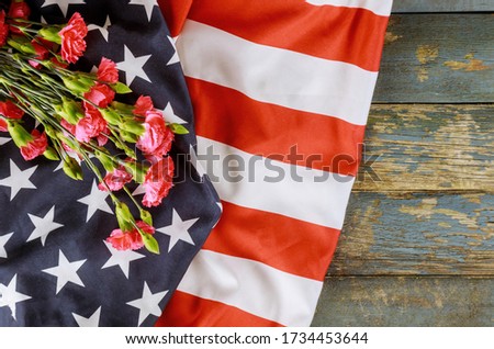 American flag on Memorial day honor respect patriotic military US in pink carnation old wooden background