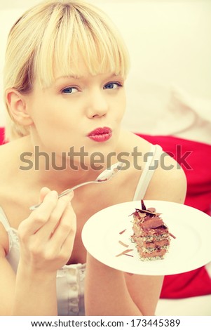 Beautiful woman on couch eating cake. Indoor.