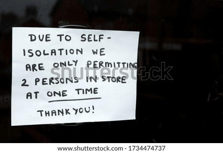 Due to self-isolation we are only permitting 2 persons in store at one time. Thank you! sign on a shop window informing people of the current changing situation with corona virus ruining business 
