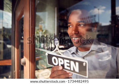 Male Owner Of Start Up Coffee Shop Or Restaurant Turning Round Open Sign On Door
