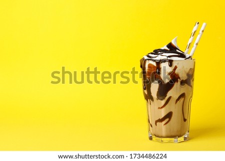 Glass of chocolate milkshake on yellow background. Summer drink Royalty-Free Stock Photo #1734486224