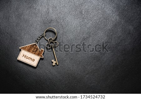 House key with home keyring on rusty wood background, copy space