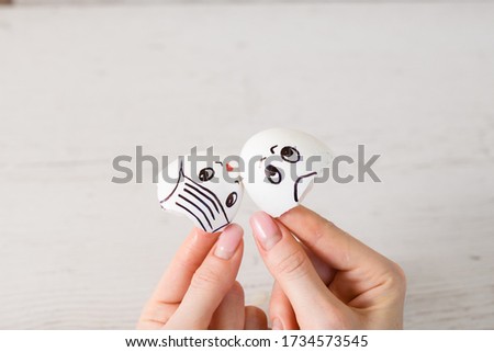 Female hand hold eggshells with drawn faces