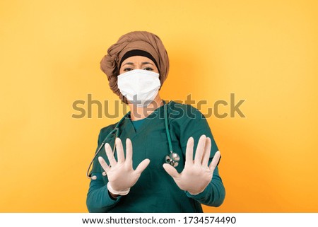 Beautiful muslim doctor girl over isolated background afraid and terrified with fear, and disgusted expression stop gesture with both hands saying: Stay there. Panic concept.