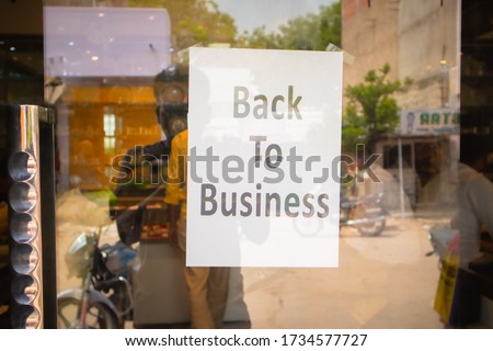 Back to business poster or signage sticked in front of store door - concept of reopening business after coronavirus or covid-19 pandemic lockdown crisis. Royalty-Free Stock Photo #1734577727