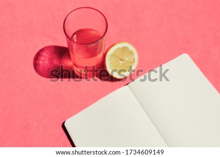 Minimalist image with a fresh lemonade and a plain-leaf notebook one summer morning in the home garden looking for inspiration