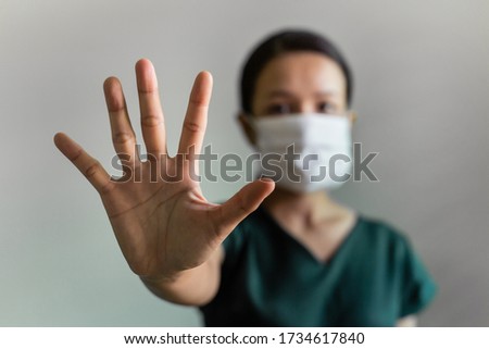 Close up hand focus masked Asian woman makes stopping hand gestures. Studio shot Coronavirus or Covid-19 concept. 