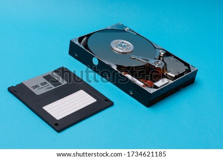 Close up of the inside of a Hard Drive and floppy disk on blue background. data storage concept. Topical data storage unit repairs. information backup and security concept. file recovery services.