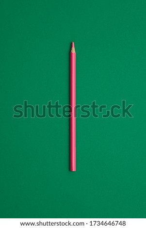 Pink magenta colored pencil isolated on green background