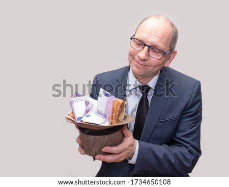 A man in a suit and hat with a bunch of money in his hands. A man is happy with wealth.