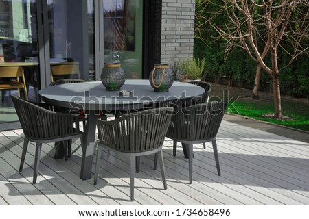 A table and four chairs in the exterior of a country house. Exterior elements