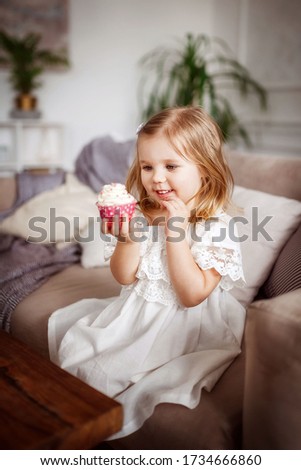 Baby girl eating sweet cupcake, laughing, delicious.