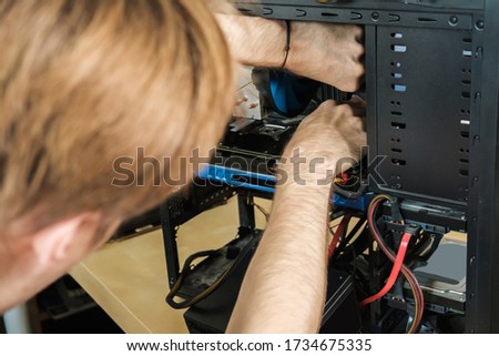 Man repairs a computer system unit, changes parts, video card and hard drive. Computer Repair Wizard.
